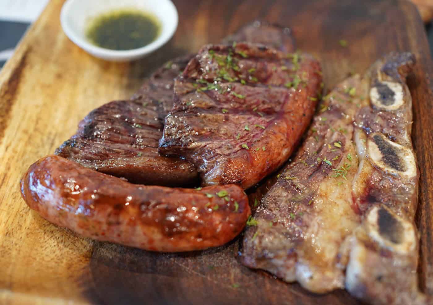 Image of grilled meat and chimichurri from the Caminito website