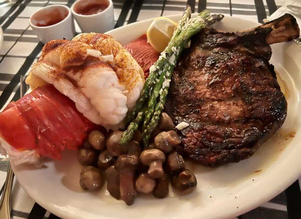 Steak, lobster tail, asparagus, and mushrooms on a plate at Gibson's.